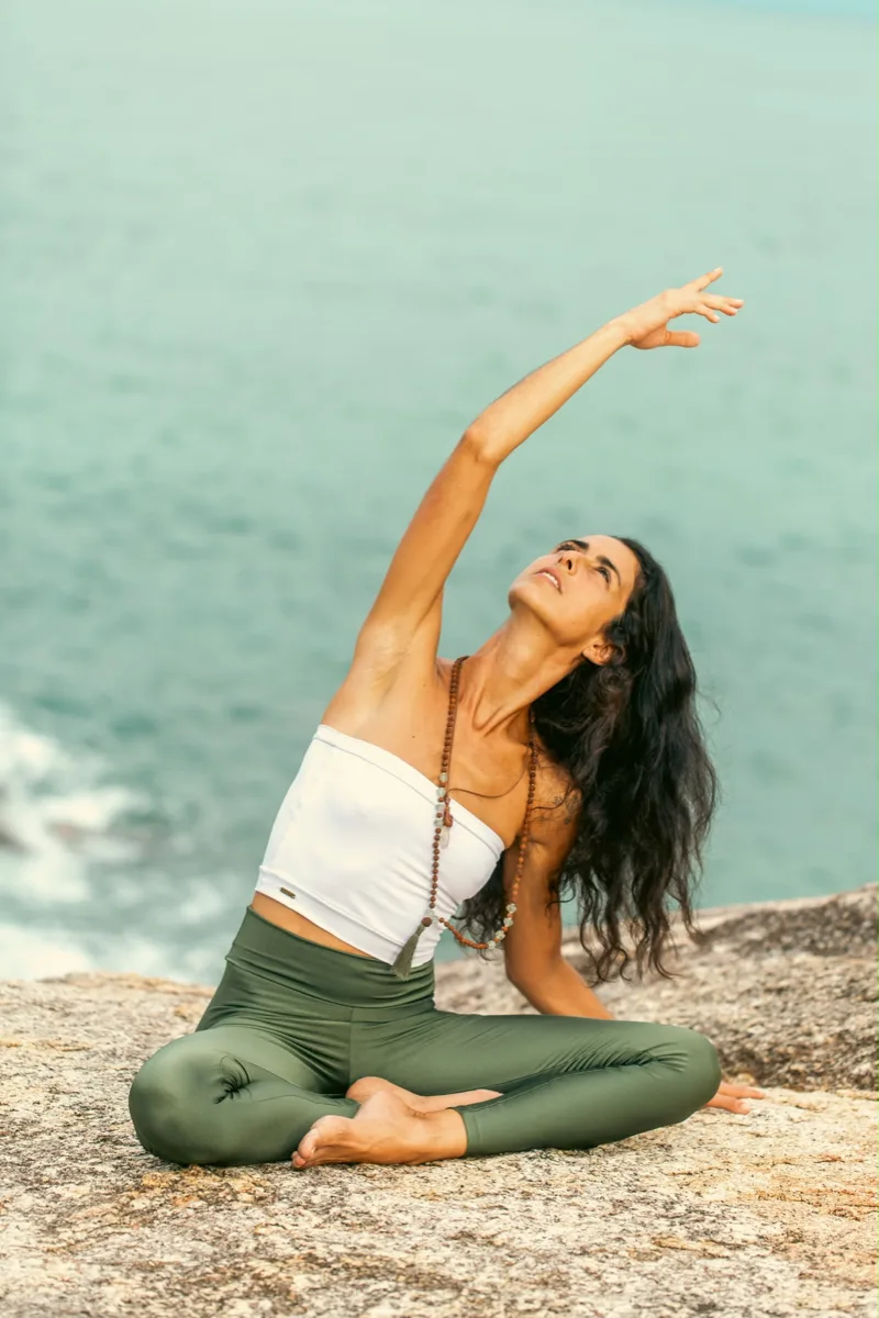 Marcela stretching on a rock by the sea